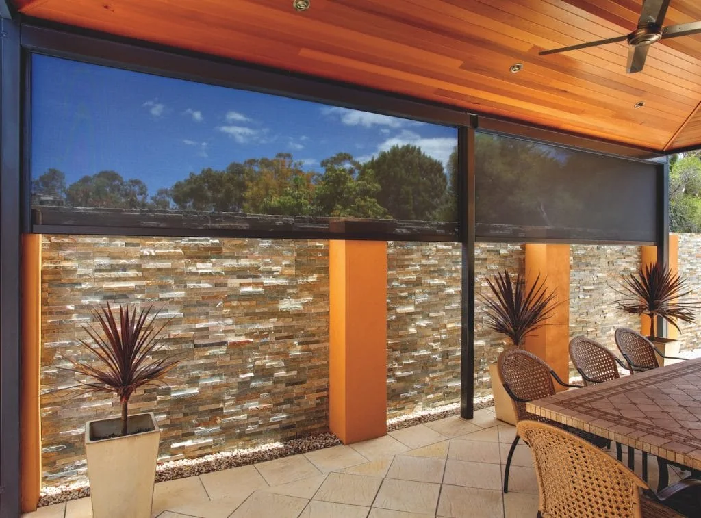 Manual exterior zipper shades lowered around a covered patio dining area.