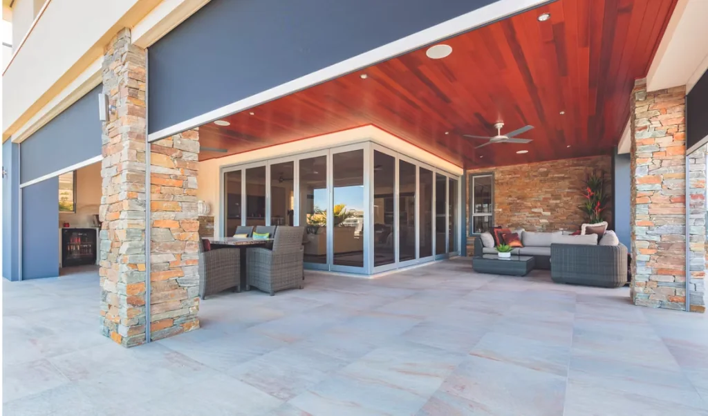 Outdoor roller shades lowered over openings in a covered lanai with seating.